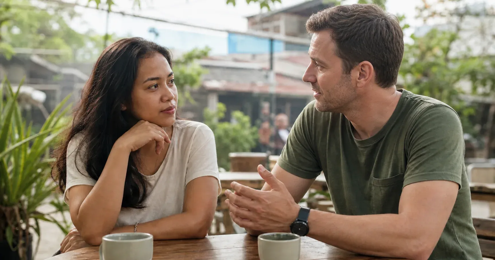 A Filipina and her partner having an attentive conversation at an outdoor cafe